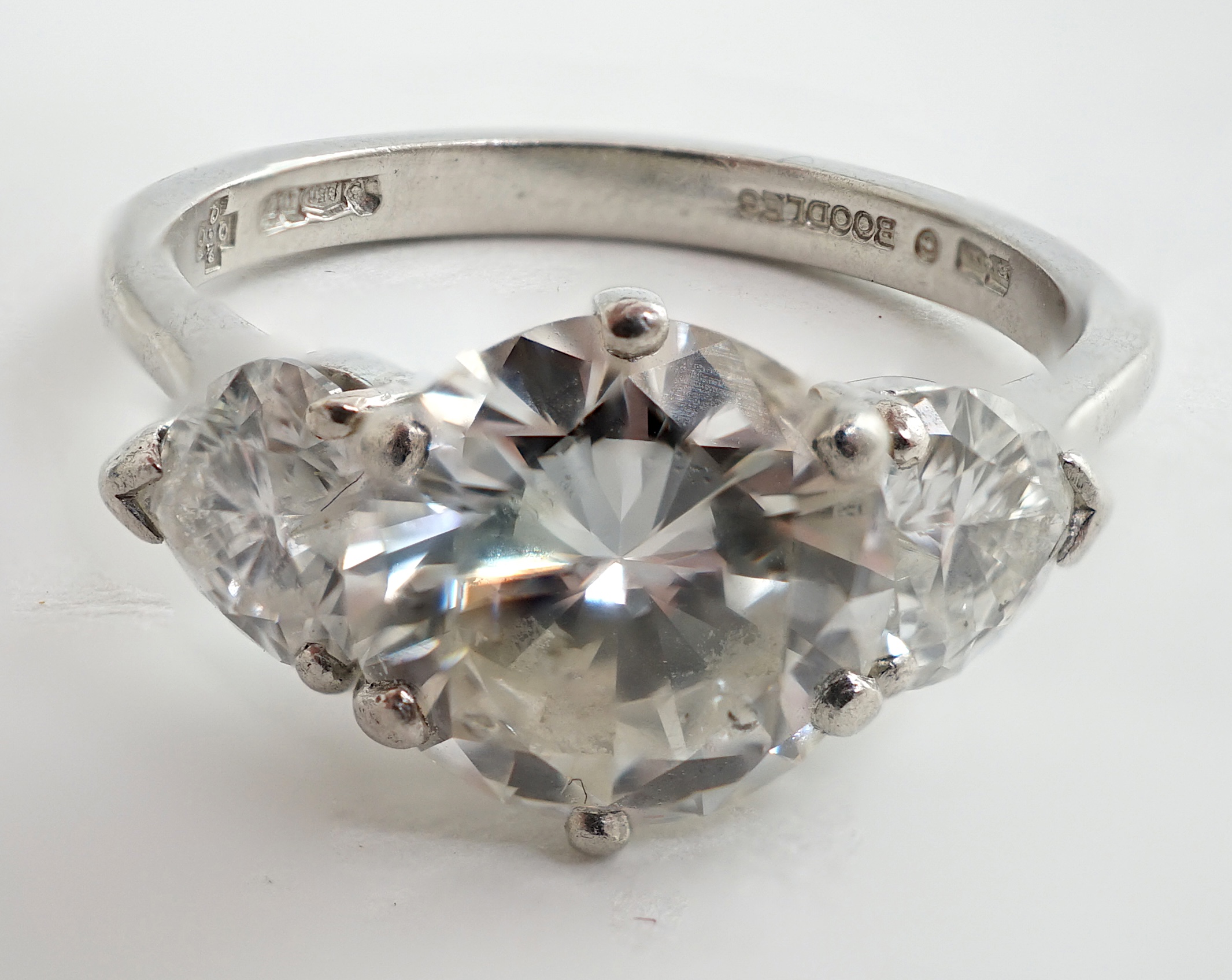 A modern platinum and single stone diamond ring, with two stone heart shaped diamond set shoulders